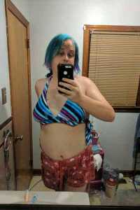 Zoe in a cute blue, purple, and white striped bikini top and red shorts with white hearts in front of the bathroom mirror